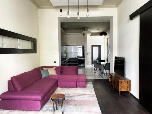 een woonkamer met een paarse bank en een keuken bij Deluxe Cosmopolitan Apartment Budapest, with Private Parking in Boedapest