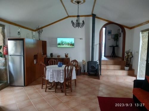 a kitchen and dining room with a table and a refrigerator at O Cantinho das Lages in Covas