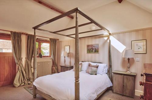 a bedroom with a canopy bed with white sheets at The Clock Tower & The Dairy - Two x 2 Bed Barns with Indoor Pool in Checkendon