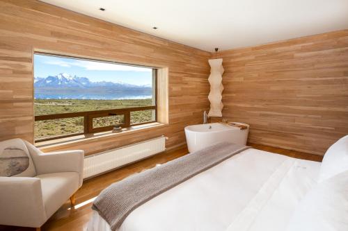 um quarto com uma cama e uma grande janela em Tierra Patagonia em Torres del Paine