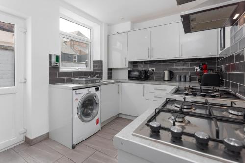 a white kitchen with a washing machine in it at Flatzy - 12 Person Townhouse with Pool Table and Ping Pong in Liverpool
