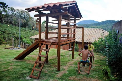 zwei kleine Jungen spielen auf einem hölzernen Spielplatz in der Unterkunft Casa Amantes da Serra Ibitipoca - Sua melhor opção! in Conceição da Ibitipoca