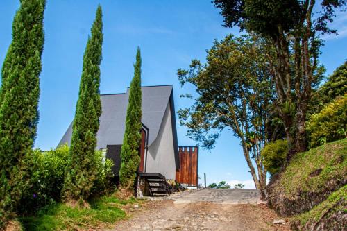 uma casa numa colina com árvores e uma estrada de terra em Hospedaje mirador la Floresta em Santuario