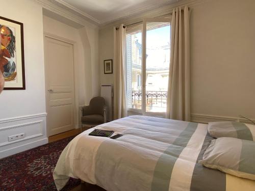 um quarto com uma cama, uma janela e uma cadeira em Nice Sunny Central Paris em Paris