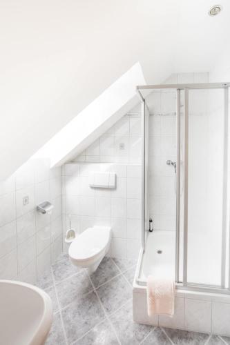 a white bathroom with a shower and a toilet at Hotel und Restaurant Piccolo in Thale