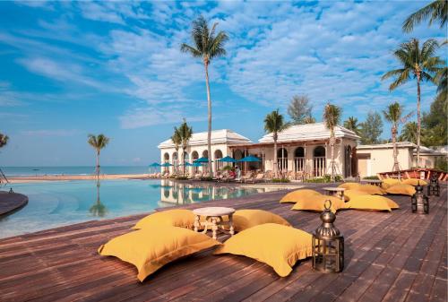 un complejo con una piscina con sombrillas amarillas junto al océano en Devasom Khao Lak Beach Resort & Villas, en Khao Lak