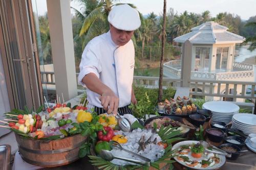 a chef preparing a buffet of food on a table at Devasom Khao Lak Beach Resort & Villas in Khao Lak