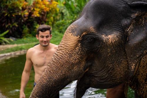a man standing in the water next to an elephant at Devasom Khao Lak Beach Resort & Villas in Khao Lak