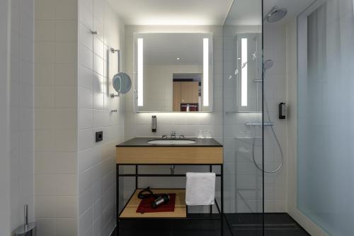 a bathroom with a sink and a mirror at IntercityHotel Herford in Herford