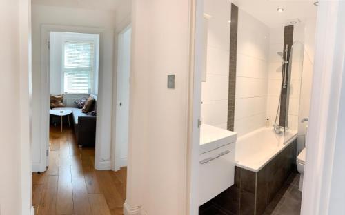 Baño blanco con lavabo y bañera en Central Location 2 bed flat, Zone II, London NW6 en Londres