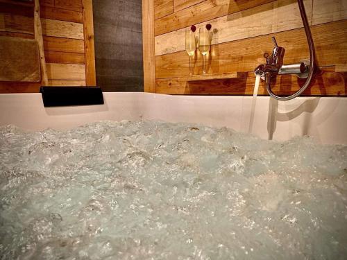 a bath tub filled with water next to a tap at Le Sanglier Amoureux in Érezée