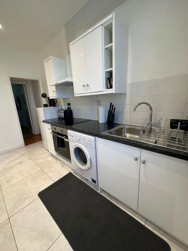 a kitchen with a washing machine and a sink at Notting Hill Guest Flat in Ealing