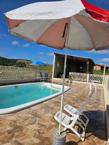 um guarda-chuva e uma cadeira ao lado de uma piscina em Sitio Aconchego Verde Guararema em Guararema