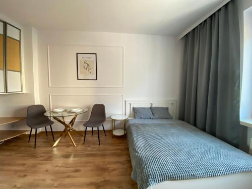 1 dormitorio con 1 cama, mesa y sillas en Apartament WHITE, en Kielce