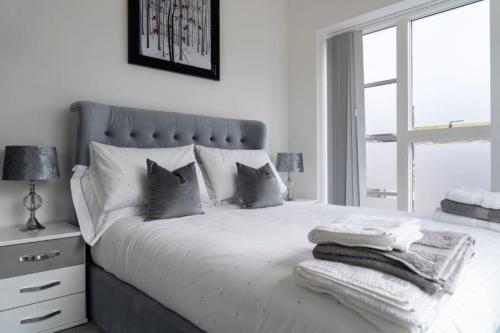 a white bedroom with a large bed with a window at The Sidings, Luxury Penthouse, Haworth in Haworth