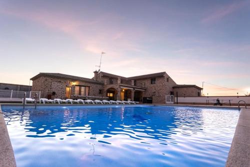 a large swimming pool in front of a house at Casa Rural El Abuelo Mauri 4* En Toledo in Mascaraque