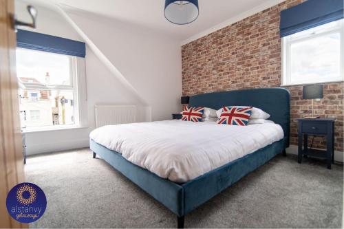 a bedroom with a blue bed and a brick wall at The Lookout in Hythe
