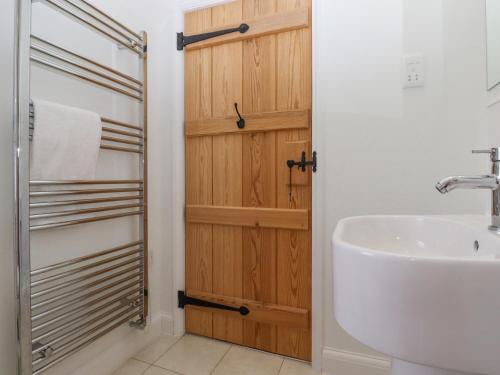 een badkamer met een wastafel en een houten deur bij Mountfield Farm Cottage in Wavehorne