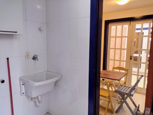a bathroom with a sink and a table and a chair at Casa com garagem - 300m da Rua das Pedras in Búzios