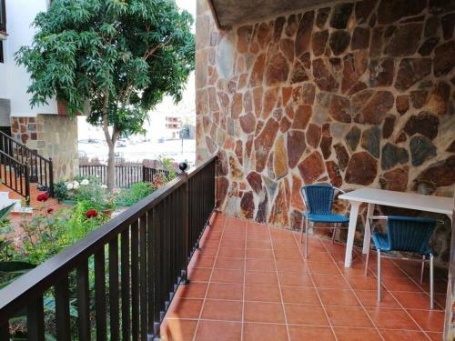 a balcony with a table and chairs and a stone wall at Casa Carolina 2 in Playa de Santiago