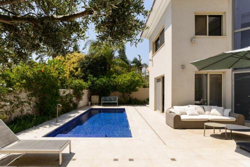 a backyard with a swimming pool and a house at Maison d architecte in Herzelia 