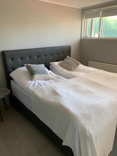 a bedroom with two beds with white sheets and a window at Mengi Apartments Keflavik in Keflavík