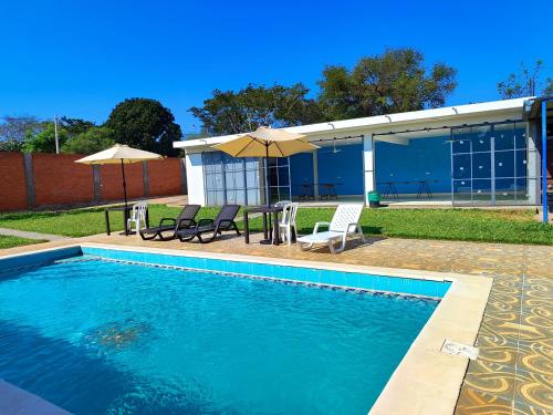a swimming pool with chairs and umbrellas next to a building at ALOJAMIENTO ASPEN HOME in San Lorenzo de la Frontera