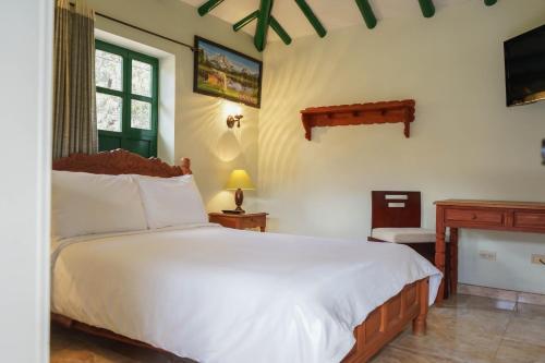 a bedroom with a large white bed and a fireplace at Hotel Beth Sarim By Legendary in Villa de Leyva