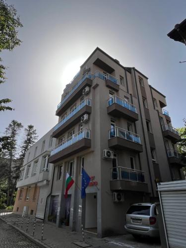 un grand bâtiment avec deux drapeaux devant lui dans l'établissement APARTHOTEL VICTORY SOFIA, à Sofia