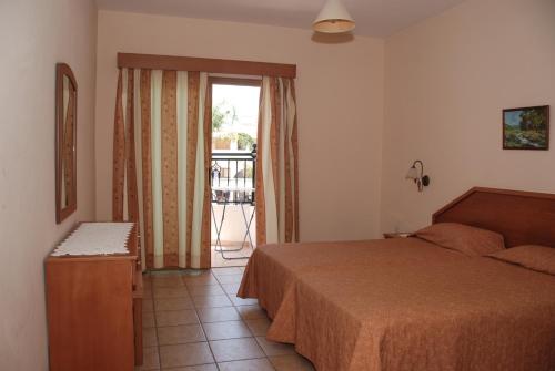 a bedroom with a bed and a door to a balcony at Kotzias Beach Apartments in Pissouri