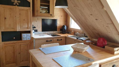 una cocina con armarios de madera y una mesa en una habitación en BARMADZA Mazots de Charme en Demi-Quartier