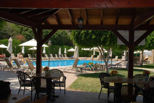 a patio with tables and chairs next to a pool at Kotzias Beach Apartments in Pissouri