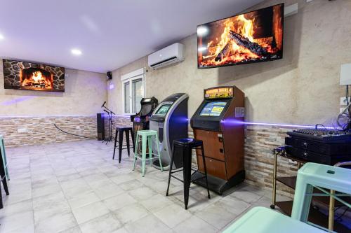 a room with two arcade games and a tv on the wall at Casa Rural El Abuelo Mauri 4* En Toledo in Mascaraque