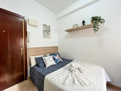 een kleine slaapkamer met een bed met een blauwe deken bij Estudio Augusto Acogedor 2 in Madrid