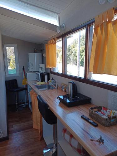 uma cozinha com um balcão de madeira e 2 janelas em Tiny house Bariloche em San Carlos de Bariloche