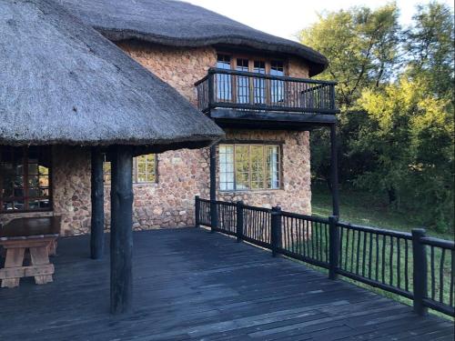 a large building with a thatched roof and a deck at Schoemanshof in Potchefstroom