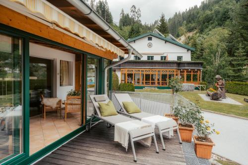eine Terrasse mit einem weißen Sofa und Stühlen auf einer Terrasse in der Unterkunft Ferienwohnungen Badbruckerweg- Bad Gastein in Bad Gastein