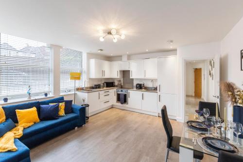 a living room with a blue couch and a kitchen at Modern flat in central golders green in London