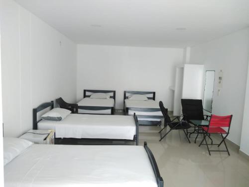 a room with four beds and two chairs at Hotel Aguazul Plaza Centro in Aguazul