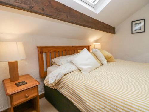 - une chambre avec un lit et une table avec une lampe dans l'établissement Old Peat Cottage, à Grizebeck