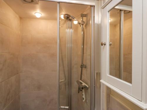 La salle de bains est pourvue d'une douche avec une porte en verre. dans l'établissement Old Peat Cottage, à Grizebeck