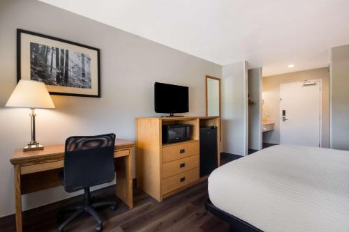 a bedroom with a bed and a desk with a television at SureStay Plus Hotel by Best Western Rexburg in Rexburg