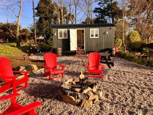 a group of red chairs and a fire pit in front of a tiny house at Ballydorn Stay in Killinchy