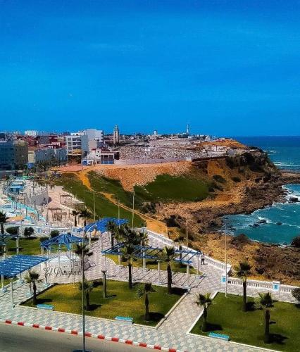a view of a beach with palm trees and the ocean at La Maison Haute Larache Morocco in Larache