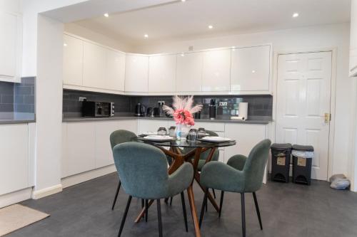 a dining room with a table and chairs in a kitchen at 4 bedroom home - free parking by Ideel Apartments in Milton Keynes in Wolverton