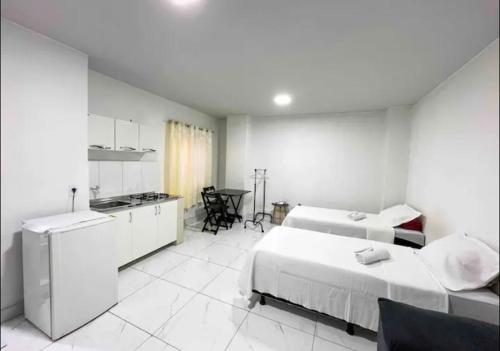 a white room with two beds and a kitchen at Apê 202 in Brasilia