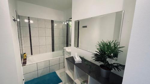 La salle de bains est pourvue d'une baignoire et d'une douche avec une plante. dans l'établissement Les Essarts T3, à Bron