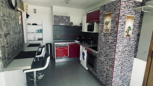 une cuisine avec des placards rouges et un mur en briques dans l'établissement Les Essarts T3, à Bron