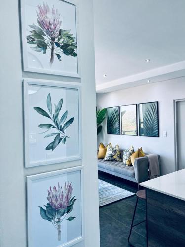 una sala de estar con 2 pinturas de flores y un sofá en @ORRIE Apartments Infinite, en Johannesburgo