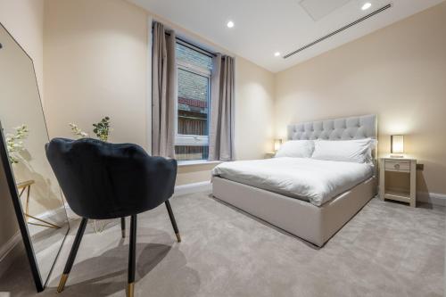 1 dormitorio con cama, ventana y silla en Candler Mews, en Twickenham